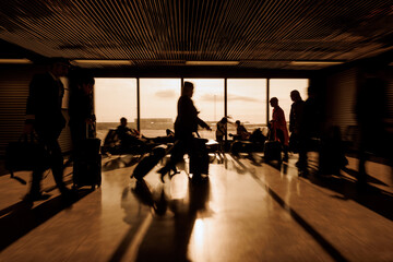 Pilot and Stewardess at airport with people sitting and walking with luggage through the departure area, motion blur shot. Travelers and transport concepts.