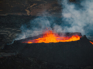 Unique view of the erupted volcano and surroundings, boiling red hot lava flowing, pull away drone shot. Natural disaster, environment, and climate change concepts.