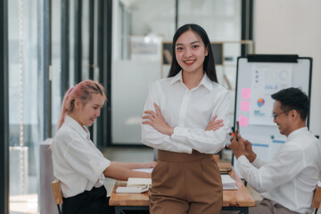 Obraz premium Confident young Asian business woman sitting with arms crossed smiling looking at camera in the office.