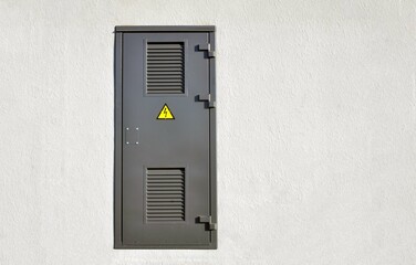 Gray metal door against a white wall. Electrical hazard.