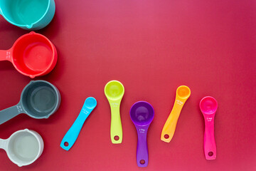 Collection of colorful measuring cups, measuring spoons use in cooking process on red background
