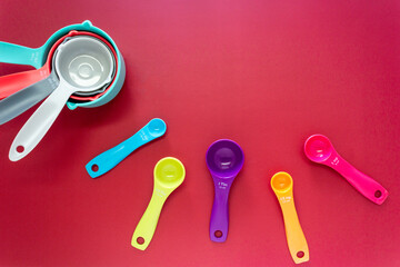 Collection of colorful measuring cups, measuring spoons use in cooking process on red background