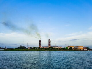 High pollution from power plant. Power plant on the coast. Ecology disaster concept. Power plant high pipes with black smoke moving up polluting atmosphere.