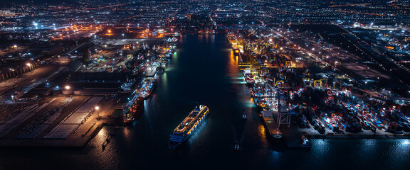 large cruise ship departing from Laem Chabang Port at night.  want to use low shutter speed to see movement of the ship. blue tone and over lighting scene photography aerial view. - obrazy, fototapety, plakaty