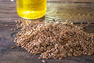 Flax seeds and a bottle of linseed oil on a wooden background. An alternative source of omega 3...