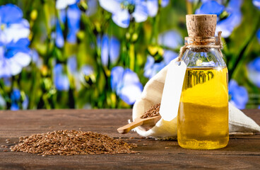 Flax seeds and a bottle of linseed oil on a wooden background. An alternative source of omega 3 vitamins and fats - obrazy, fototapety, plakaty