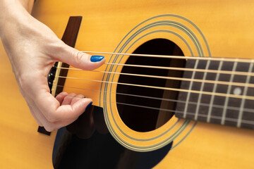 hand runs fingers along the strings of an acoustic guitar