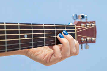 female fingers pinch the strings on a guitar.
