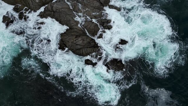 view from a drone from above of the waves in the ocean hitting the rocks in the evening aerial photography