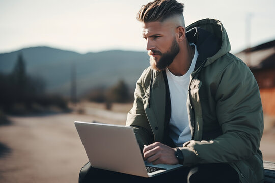 Caucasian young man is in the mountains, he travels and working on laptop, in sportswear, morning sun, copy space