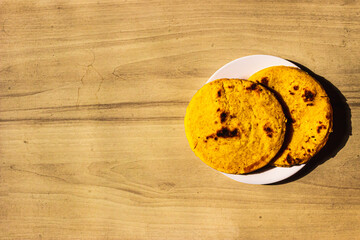 White plate with two typical Colombian arepas on wooden background