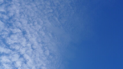 Blue sky full screen background with half mackerel sky and half clear blue sky