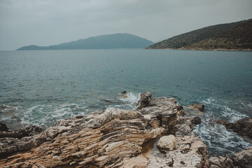 Scenic rocky beach with mountains in background in Kefalonia, Greece - 755000084