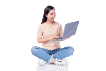 Happy young asian woman sitting on white chair with legs crossed and using laptop computer on light pink background copy space Full body young smiling happy female wearing t shirt and jeans lifestyle	