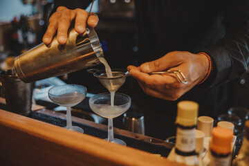 bartender pouring cocktail into glass - 755000499