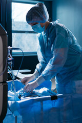 Professional Female Nurse in personal protective kit Uses Medical Computer. Doctor connects wires, medical equipment, preparation before surgery in ophthalmology clinic