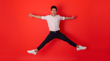Fototapeta na wymiar Full body of young dynamic handsome Asian man smiling and jumping with arms outstretched isolated on Coral color background professional photography