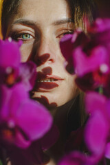 Portrait of a blonde girl against a yellow wall. Close-up with purple orchids