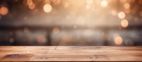 A wooden table top is shown with blurry lights in the background, creating a soft and abstract effect. The lights are out of focus, adding a subtle glow to the scene. - obrazy, fototapety, plakaty