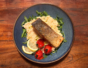 Seared salmon steak with lemon risotto, braised cherry tomatoes, arugula and lemon.
