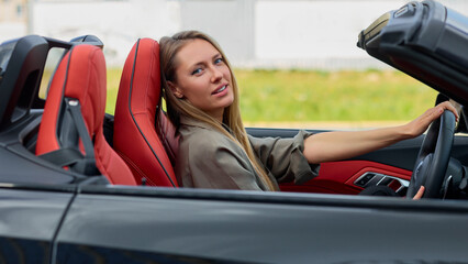 Fototapeta na wymiar Confident business woman enjoying the new ride in a sleek convertible car
