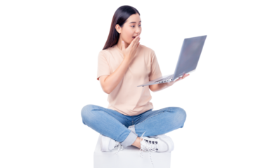 Excited young asian woman sit on white chair with legs crossed and using laptop computer on light pink background copy space Full body young smiling happy female wearing t shirt and jeans lifestyle	