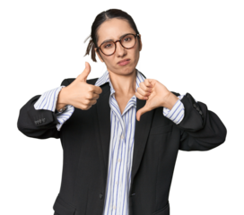 Confident young Caucasian businesswoman on studio background showing thumbs up and thumbs down, difficult choose concept