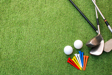 Colorful golf balls, clubs and tees lay on the green grass.