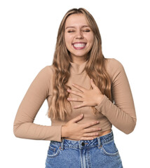 Studio portrait of a blonde Caucasian woman laughs happily and has fun keeping hands on stomach.