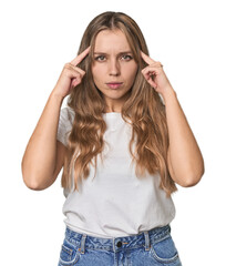 Studio portrait of a blonde Caucasian woman focused on a task, keeping forefingers pointing head.