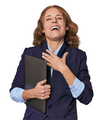 Mid-aged Caucasian with laptop in studio laughs out loudly keeping hand on chest.