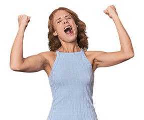 Redhead mid-aged Caucasian woman in studio raising fist after a victory, winner concept.