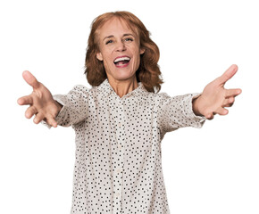 Redhead mid-aged Caucasian woman in studio feels confident giving a hug to the camera.