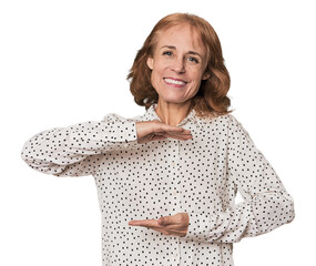 Redhead mid-aged Caucasian woman in studio holding something with both hands, product presentation.