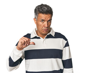 Middle-aged Latino man showing a dislike gesture, thumbs down. Disagreement concept.