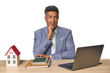 Middle-aged Hispanic businessman with real estate theme relaxed thinking about something looking at a copy space.