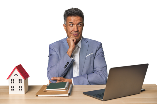 Middle-aged Hispanic businessman with real estate theme relaxed thinking about something looking at a copy space.