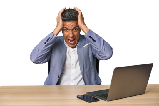 Elegant businessman at desk with laptop screaming, very excited, passionate, satisfied with something.
