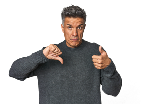 Middle-aged Latino man showing thumbs up and thumbs down, difficult choose concept