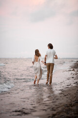 Couple in love are walking on the water along the seashore