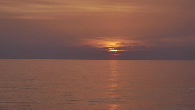 Atardecer en mar Mediterr&aacute;neo calmado, anaranjado, pasan aves volando