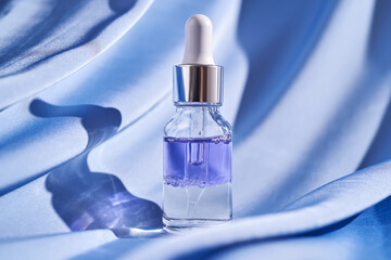 Two-component facial serum on a blue silk background.