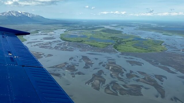 Beechcraft Bonanza airplane wingtip flies over Susitna River, Cook Inlet's Knik Arm in Alaska. Small aircraft are only way to see many areas of Alaska. Susitna flats, braided river and mud flats.