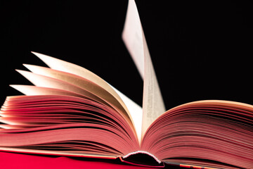 Pages of a thick book are turned on a pink and black background