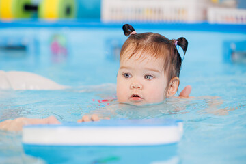 Little baby swimmer. Cute happy kid girl floating in swimming pool. Sport activity for health concept