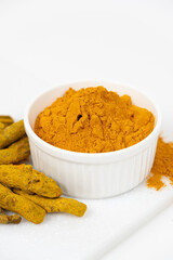 Turmeric powder, spices and dried root on white background.