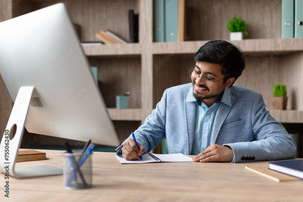Aufkleber hindu businessman sits at desktop computer taking notes in office