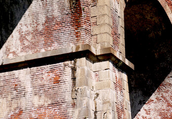 Supporting pylons of a solid red brick railway bridge with stone cornice