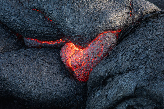 Heart shaped red hot lava on a black lava field in Hawaii, USA