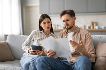 Confused spouses reviewing documents with tablet - obrazy, fototapety, plakaty